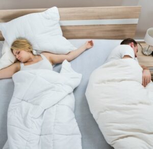 Couple sleeping with separate duvets.